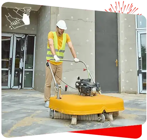 Industrial cleaning worker operating floor scrubber outside building.